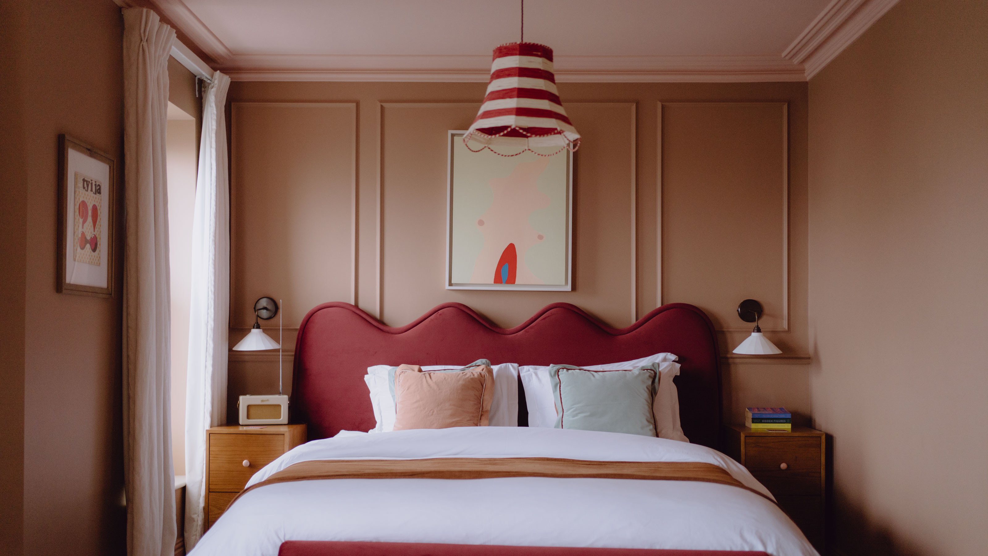 Pink bedroom with red headboard and white canvas and red and white lampshade