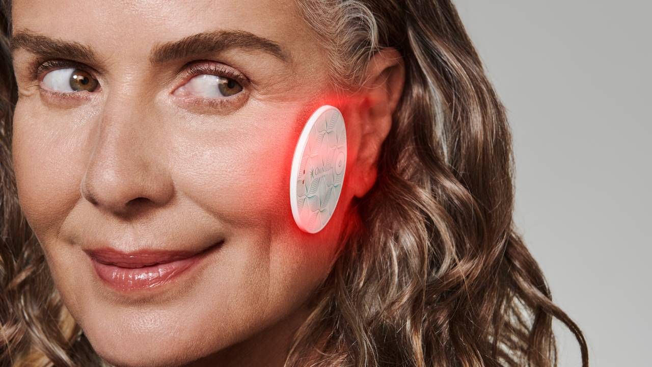 A woman using the Omnilux Mini Skin Corrector on her cheek