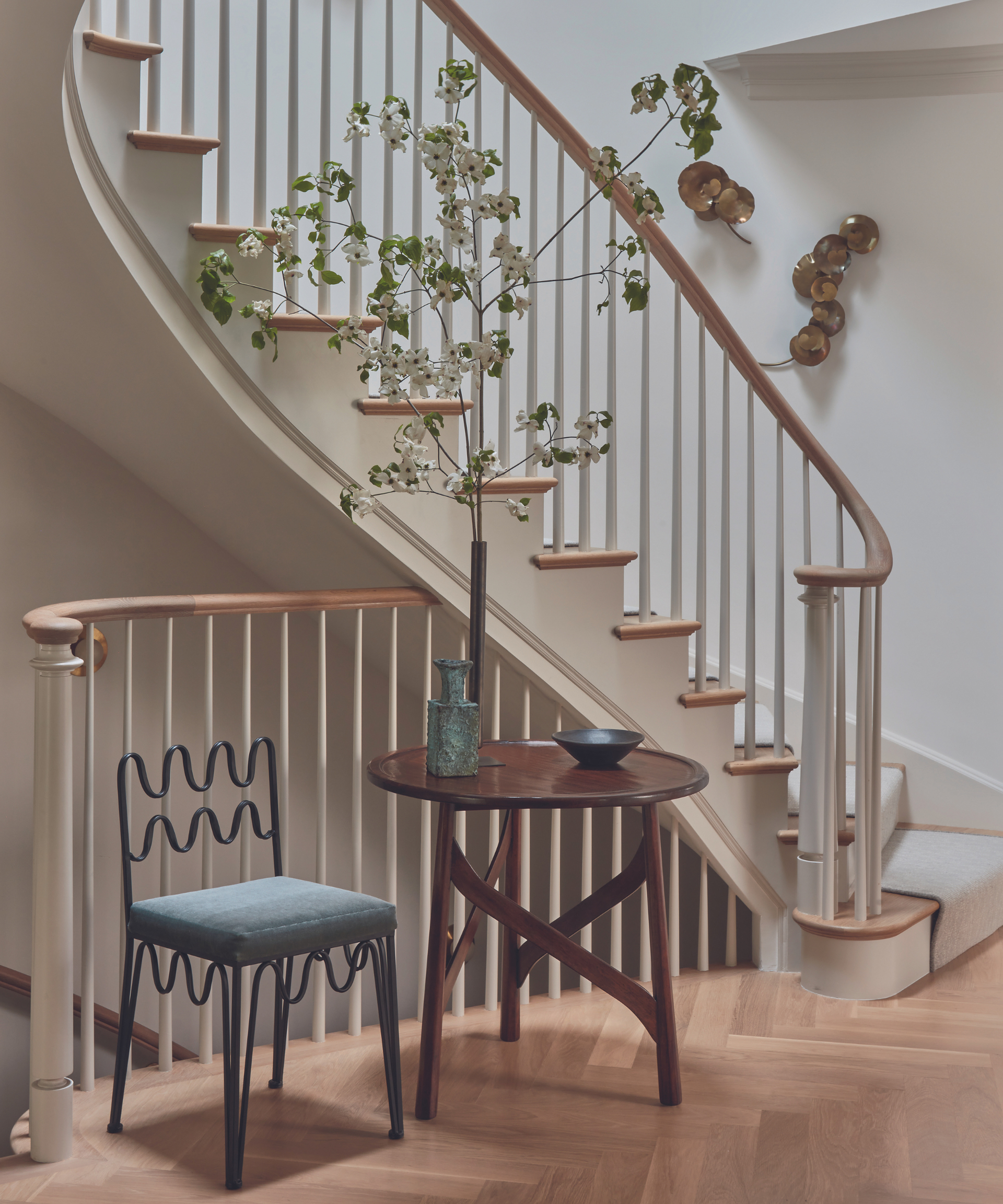 hallway with spiral staircase and side table with plant and wooden floors