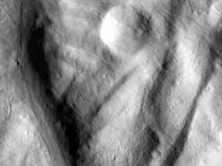This image, from NASA's Dawn spacecraft, shows rock material that has moved across the surface and flowed into a low area in the ridged floor of the Rheasilvia basin on Vesta. The image shows how impacts and their aftermath constantly reshape the landscape. This image was acquired by Dawn's framing camera on Dec. 18, 2011.