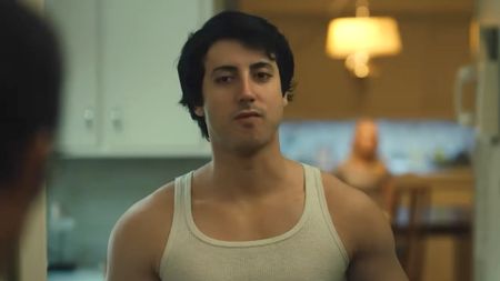 Sylvester Stallone standing in doorway in sleeveless white undershirt in I Play Rocky