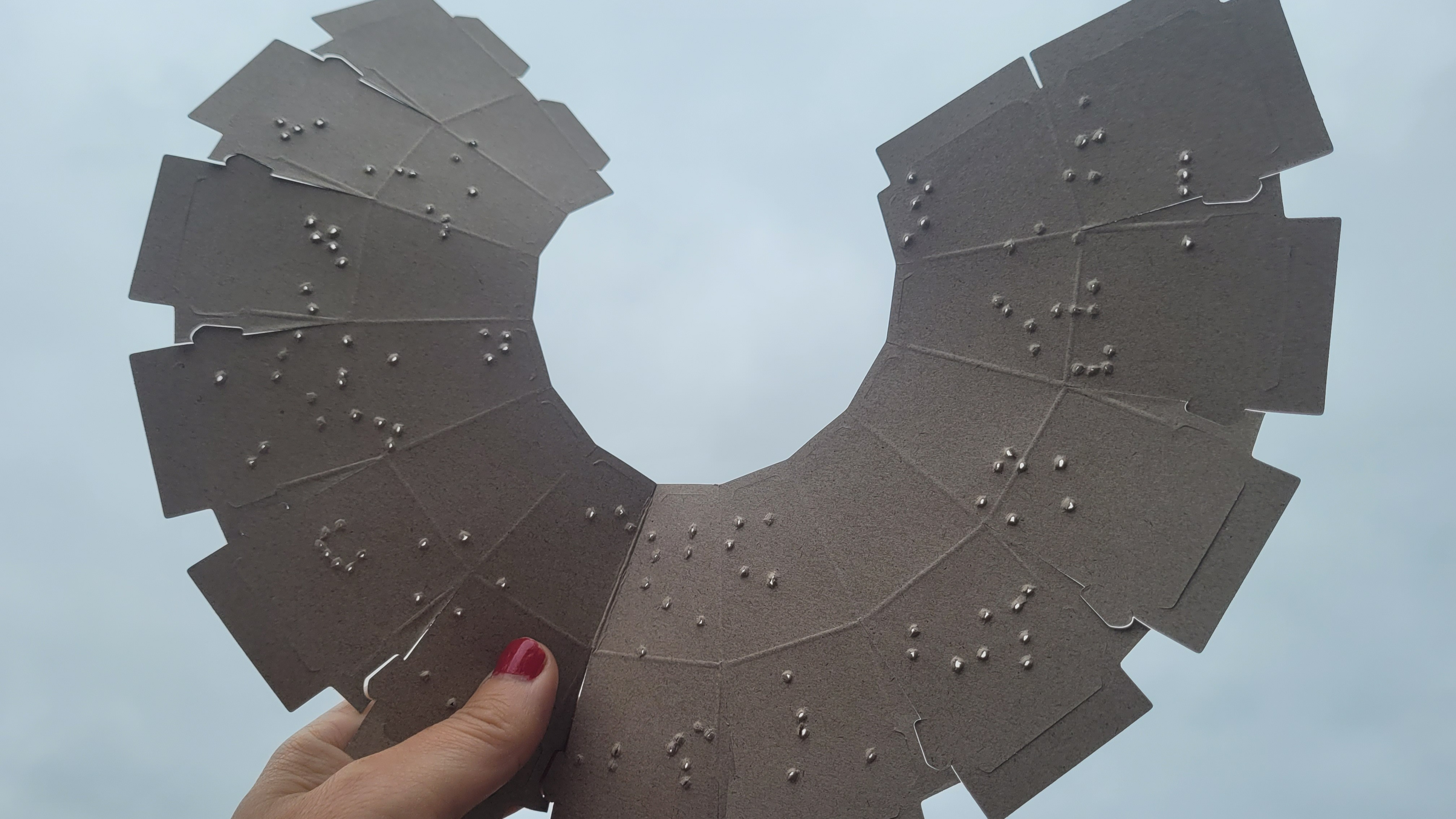 Person holding the cardboard kit up to the sky showing the locations of punched out holes