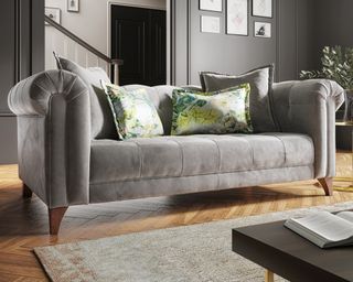 A grey velvet sofa with patterned green and yellow cushions in contemporary living room