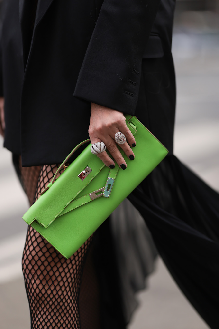 woman wearing black blazer, green clutch and short black nails