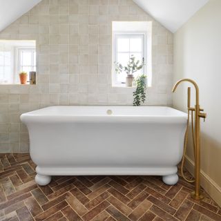 bathroom with a large traditional bath tub, with brushed brass mixer and terracotta floor tiles