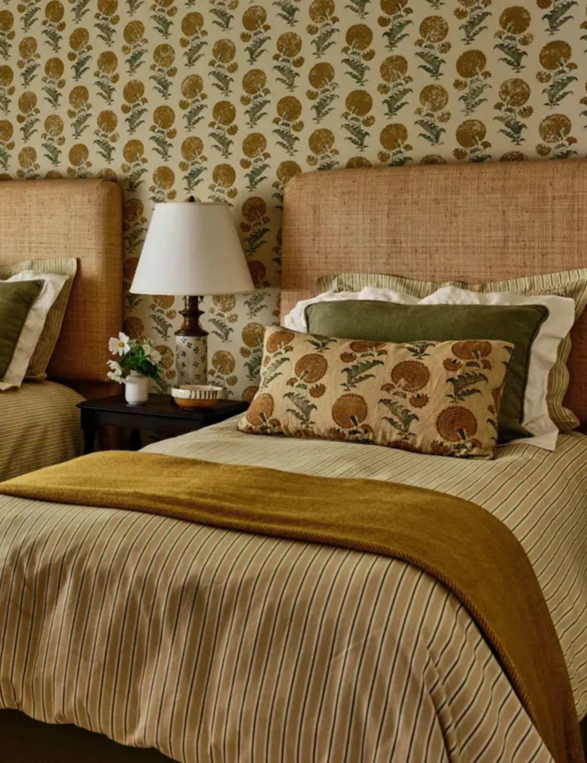 Yellow warm bedroom with printed wallpaper and matching pillows and twin beds with striped duvet