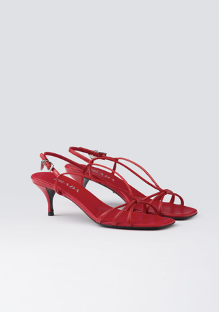 a pair of red prada sandals in front of a plain backdrop