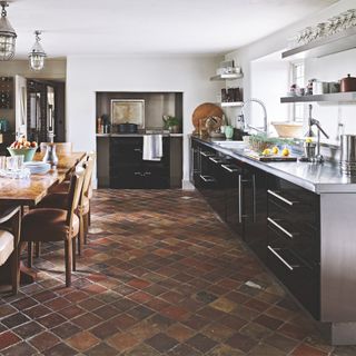 Stainless steel kitchen in country home, with wooden dining table and tiled flooring