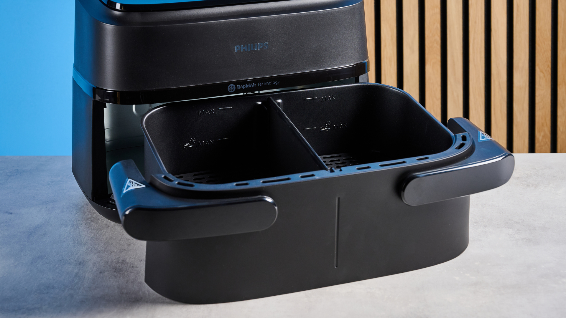 The large tray of the Philips 1000 Series FlexDrawer Air Fryer photographed in front of a blue background.