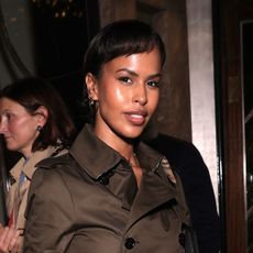 Sabrina Elba wearing a green trench coat, green pants, and plaid pumps