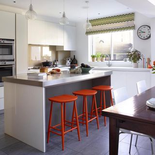 kitchen with white wall window white counter and red stools