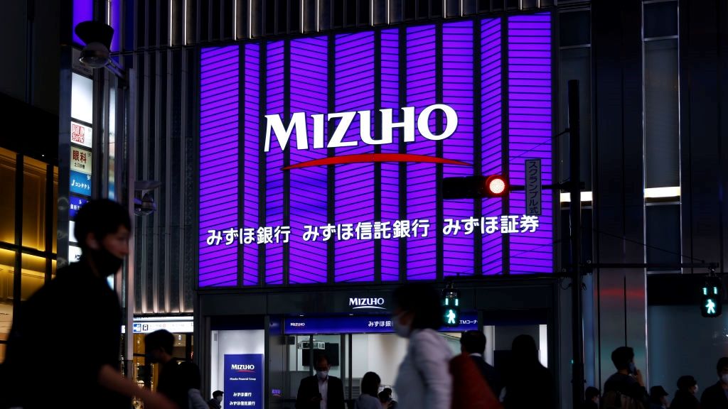 A large purple LED sign on a city street with the words Mizuho displayed