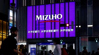A large purple LED sign on a city street with the words Mizuho displayed