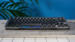 The Wooting 80HE in Ghost PCR case with black keycaps, on a stone surface with a blue background.