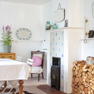 fireplace with blue and white delft style tiles and log burner in white painted dining room with vintage furniture