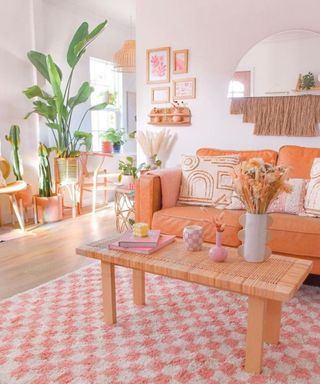 A modern boho living room with peach-colored decor and pink checkered rug