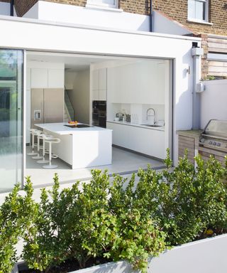 garden room with white wall white counter stool and plants