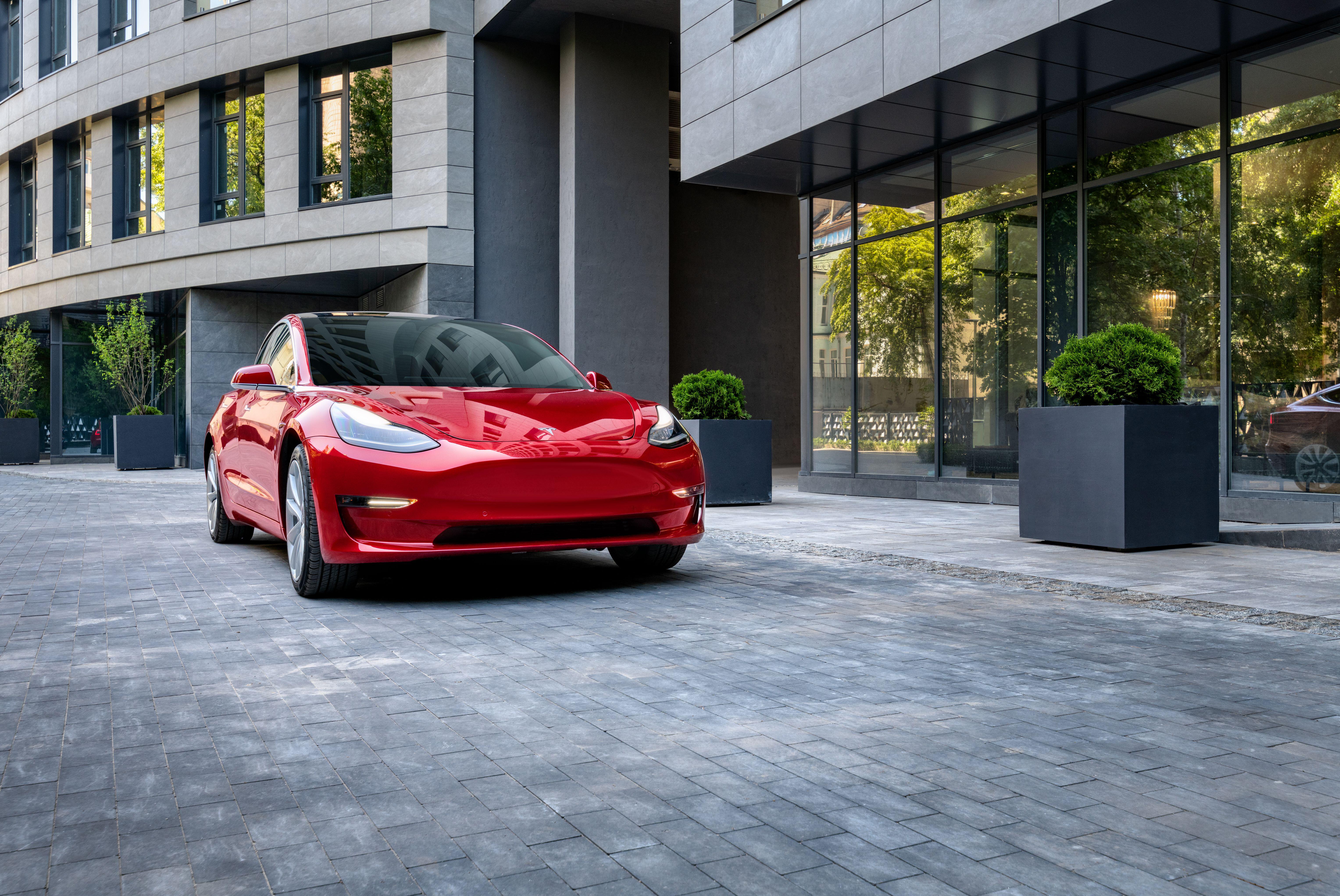 A red tesla outside of a building