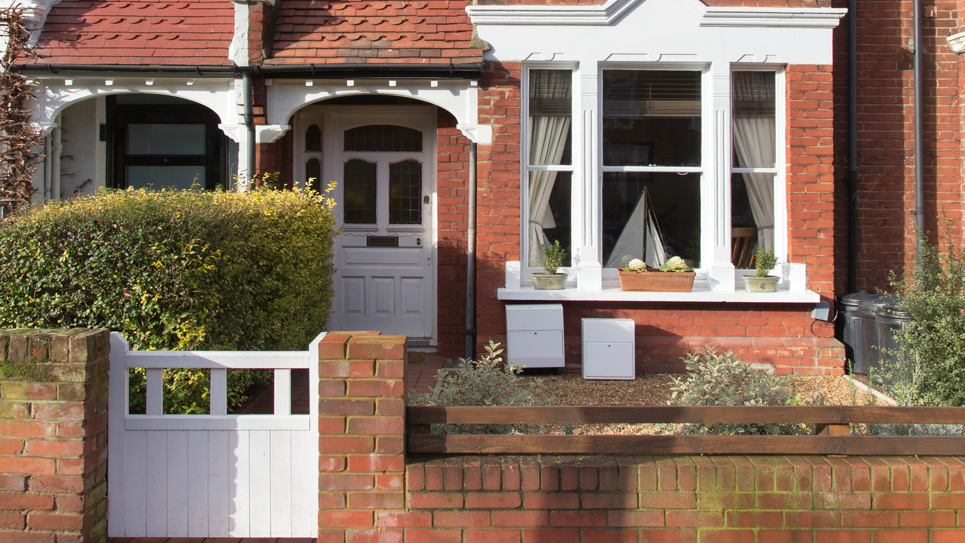 victorian house exterior with bricked wall and white window and cars