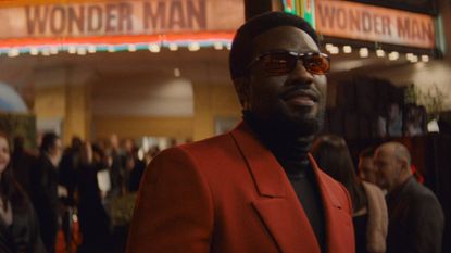 Yahya Abdul-Mateen II as Simon Williams wearing a red suit and sunglasses in Wonder Man