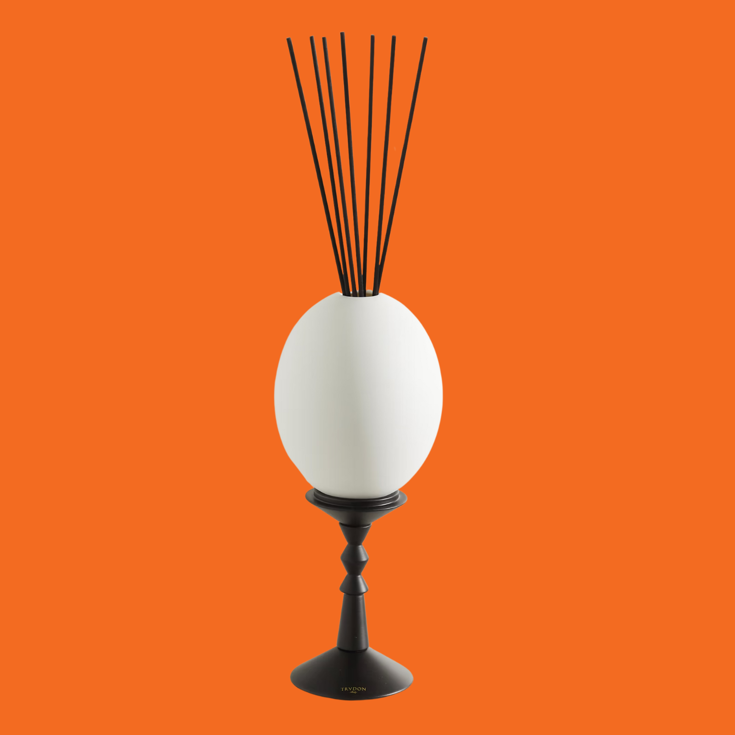 An egg-shaped reed diffuser against an orange backdrop