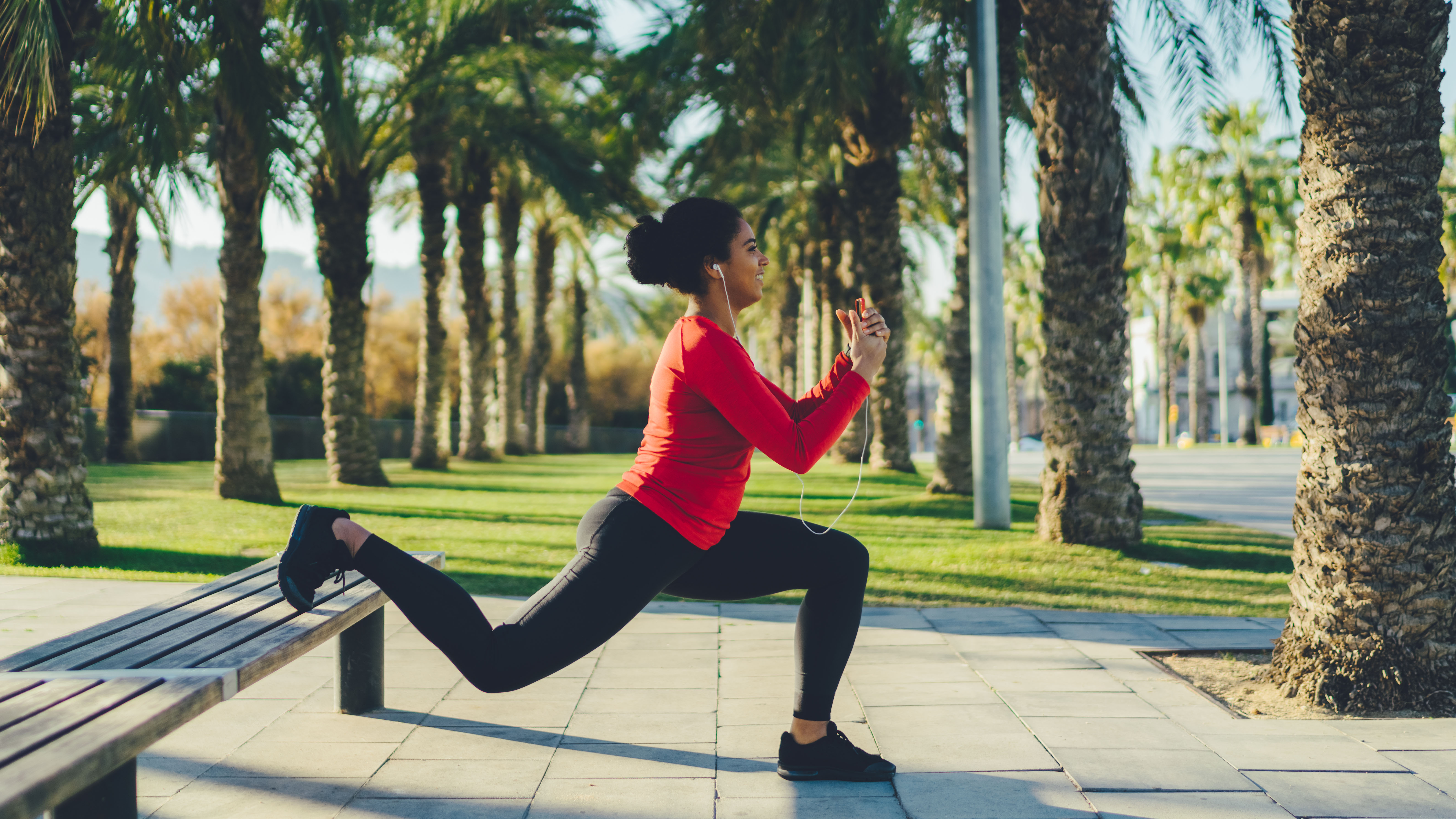 Woman performing bulgarian split squat on sunny street