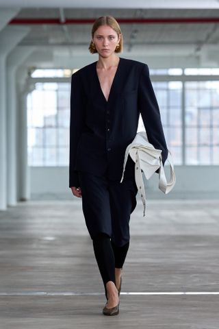 a model wears a leggings outfits of black leggings, black shorts, blazer on Tibi Spring 2025 runway.