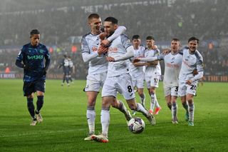 Swansea City players celebrate a goal against Stoke City in the Championship in April 2024.