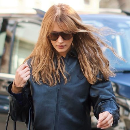 Bella wears oversize sunglasses and a leather jacket.