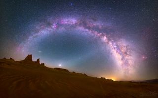 the milky way shines in the sky above a desert