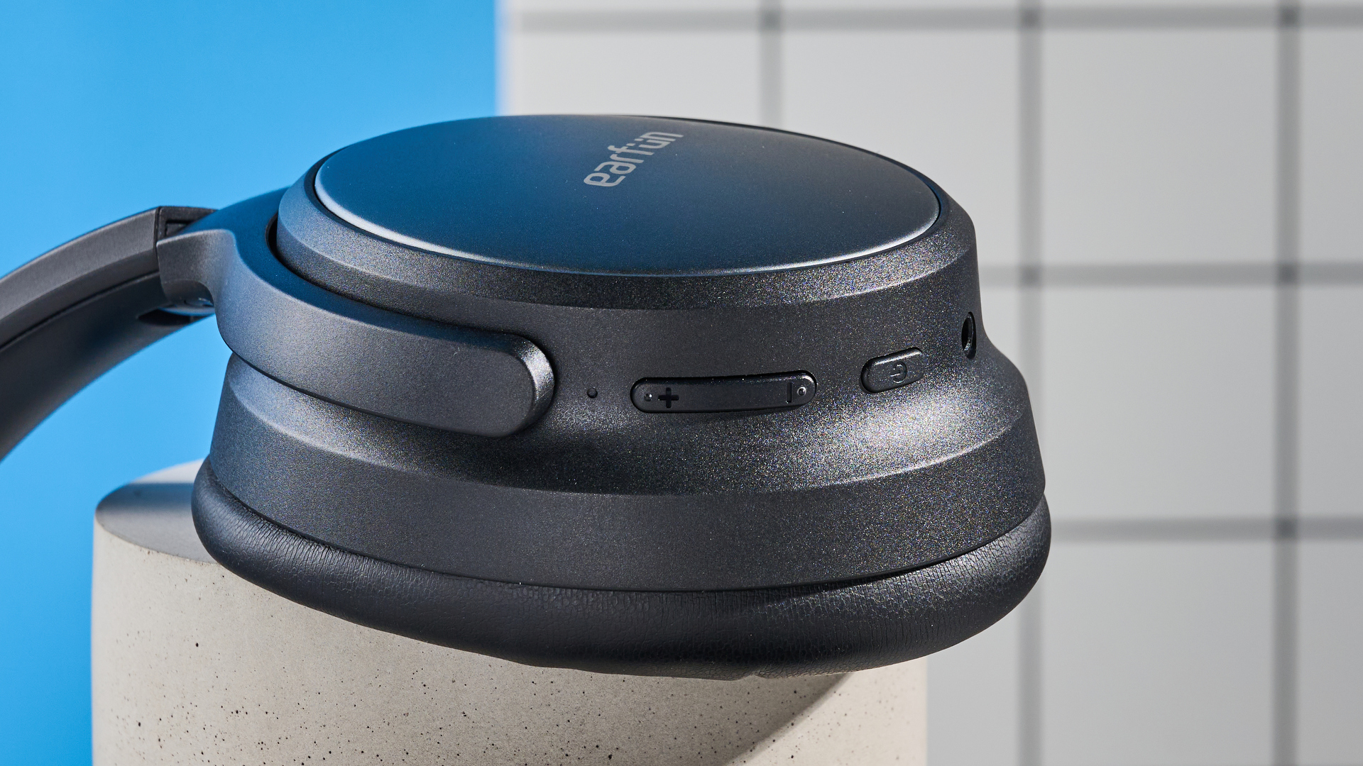 the earfun tune pro headphones, in black, with soft pleather cups, and gray cups, photographed against a blue background
