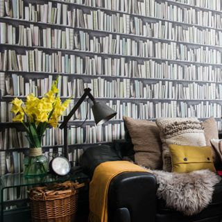 living room with bookshelves wallpaper and leather sofa with cushions