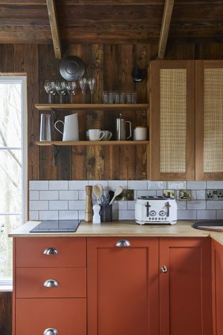 A kitchen with rust lower cabinets and wooden upper cabinets