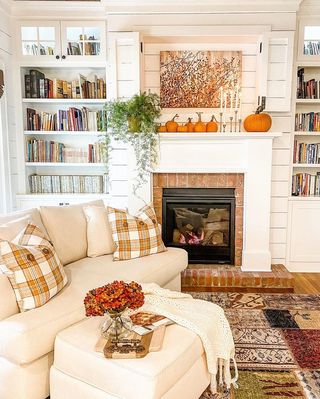 pumpkins and gourds on a mantelpiece in a living room with beige sofa and check cushions
