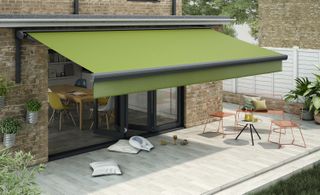 paved terrace with a large green awning extending out from the house to provide shade