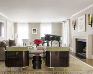 A living room with a white fireplace, black grand piano and black art deco-style armchairs