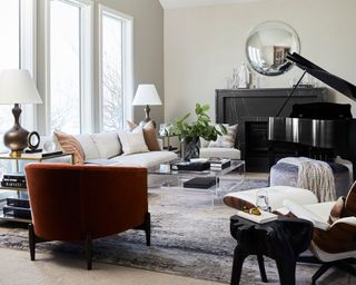 Modern living room with grand piano, seating area with rug, sofa multiple armchairs