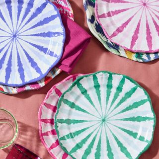 collection of brightly coloured melamine plates on a pink tablecloth