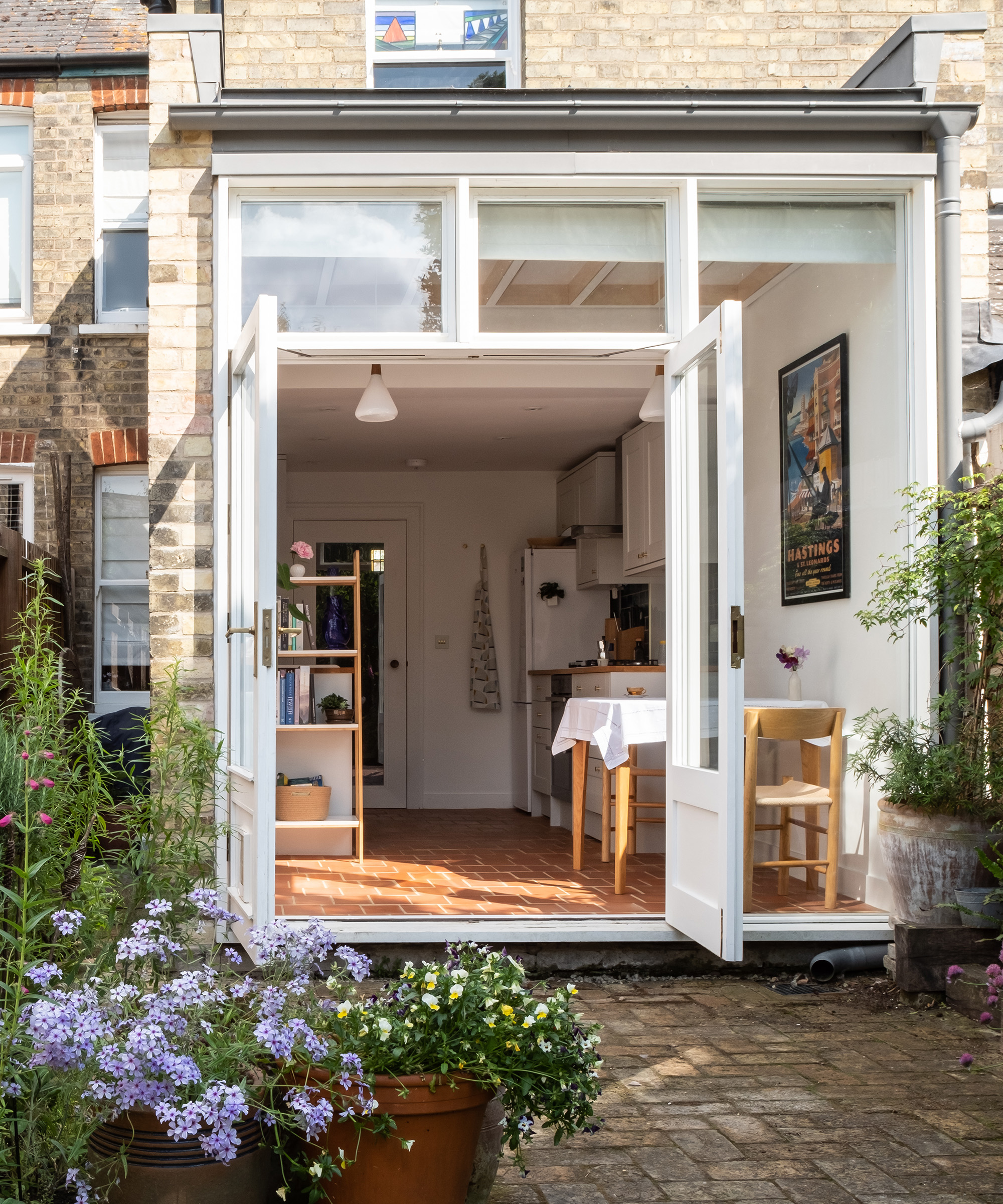 Open French doors with white frames looking into a small kitchen-diner extension
