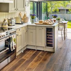 Peninsula kitchen with cream cabinetry and wooden flooring