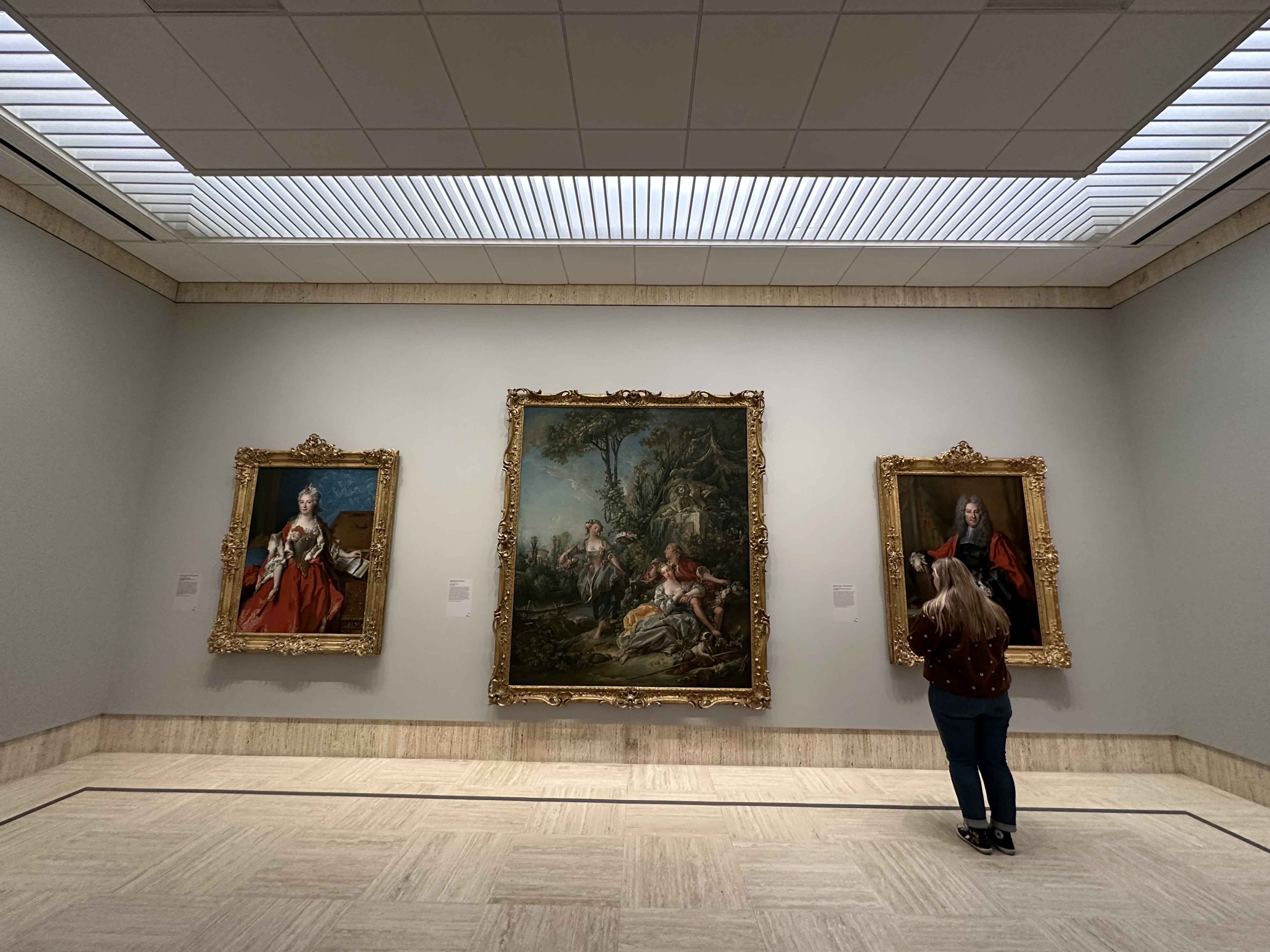 A young woman stands in front of a painting at the Timken Art Museum