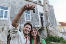 A young couple that has retired abroad poses with keys to their new home.