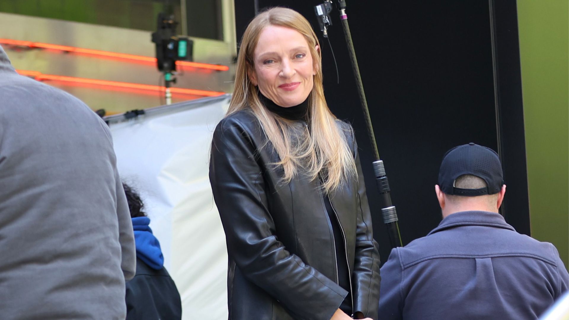 Uma Thurman wears dark wash jeans with a leather jacket and white Onitsuka Tiger Trainers