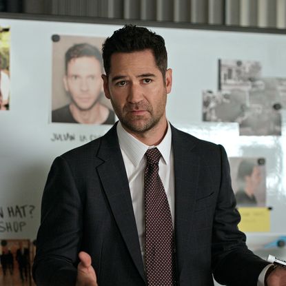 Manuel Garcia-Rulfo as Mickey Haller, standing in front of a whiteboard and window blinds, in episode 305 of The Lincoln Lawyer.