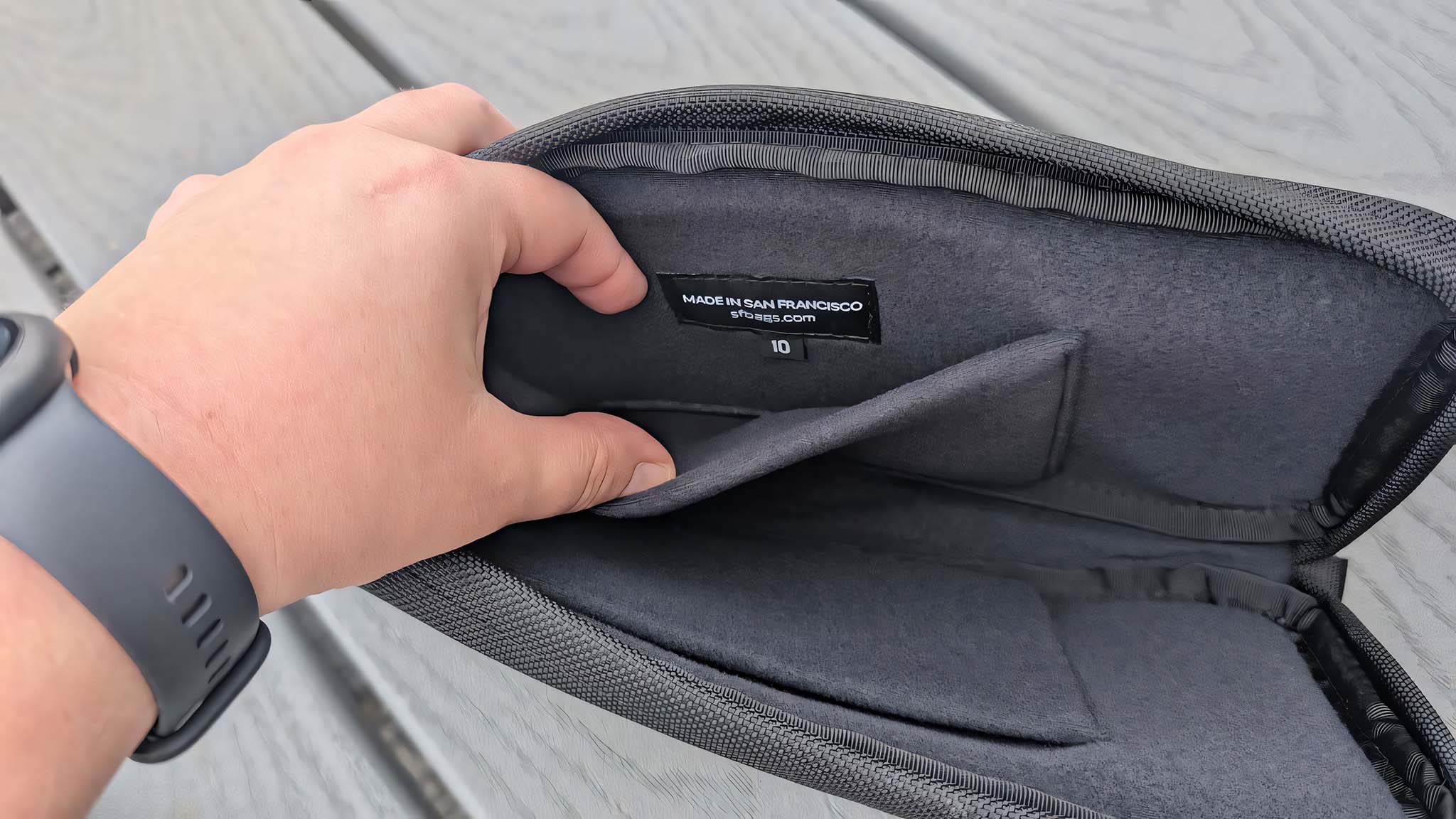 A hand holding the inner pocket of the Waterfield ROG Ally X Magnetic Case open.