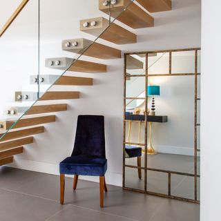 Wooden staircase with chair and big mirror underneath