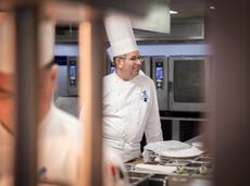 Man in a white chefs hat in a kitchen 