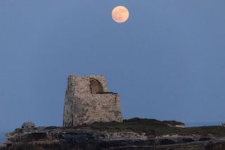 The full moon rises behind over the Tower of Roca Vecchia in Roca Vecchia, Lecce, Italy, on June 21, 2024.