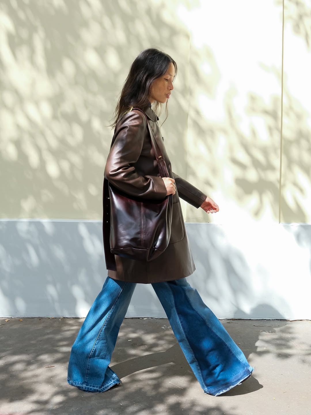 Woman wearing long, baggy jeans fall denim trend 2025.