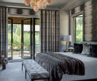 bedroom with gray scheme and bubble light fitting doors open to patio